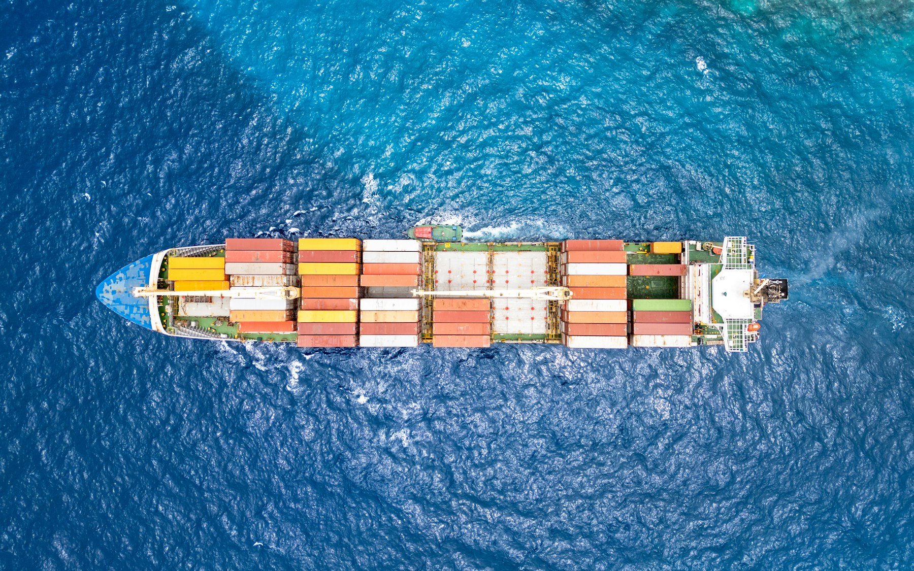 A cargo vessel underway in open ocean, viewed from above